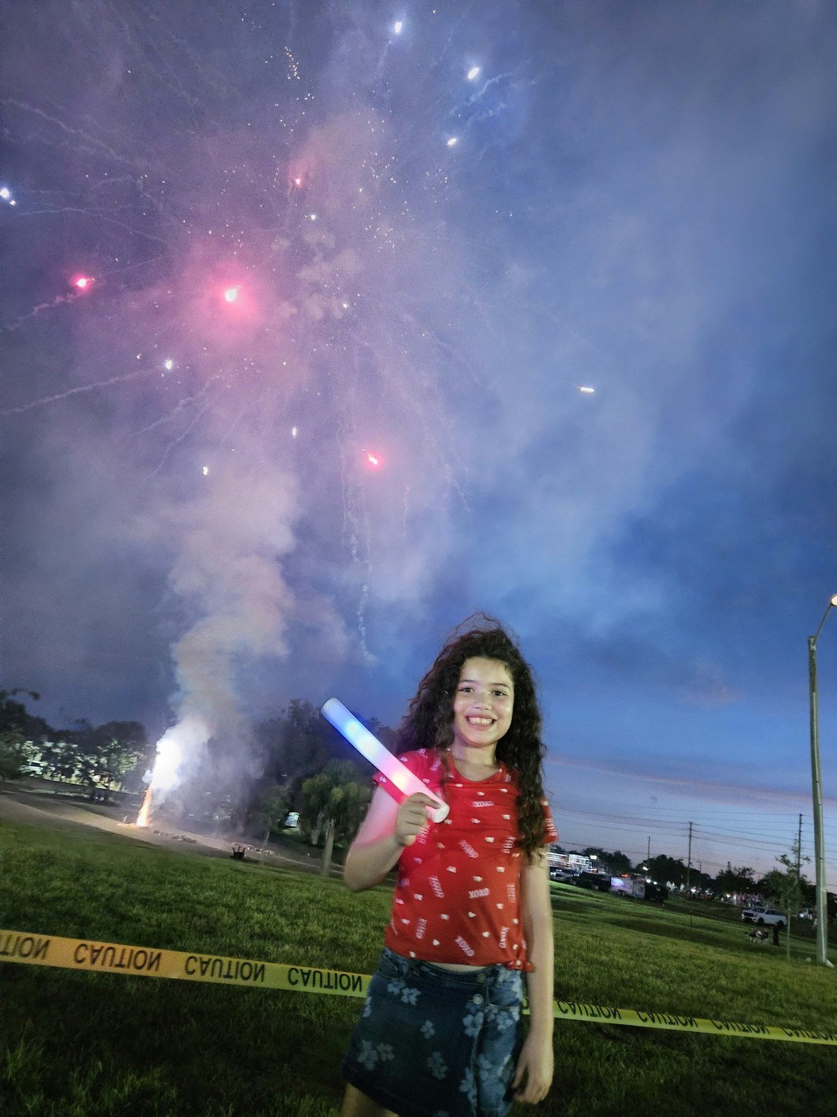 Ada holding a glow stick under fireworks at night